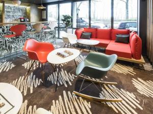 a room with a red couch and chairs and tables at ibis Mulhouse Centre Filature in Mulhouse