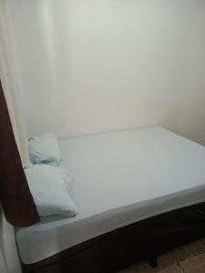 a white bed with two pillows on it at Hotel e Galeria Vizza in Goiânia