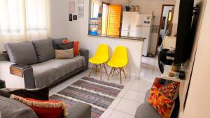 a living room with a couch and two yellow chairs at Casa Martinez in Mongaguá +21 photos