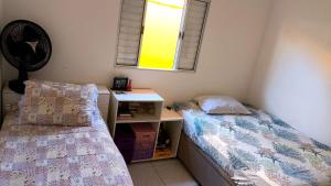 a bedroom with two beds and a desk and a window at Casa Martinez in Mongaguá