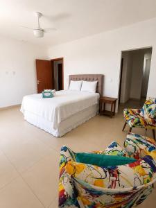 a bedroom with a white bed and two chairs at casa amplia y luminosa en porto da barra in Búzios +31 photos