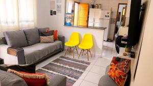 a living room with a couch and two yellow chairs at Casa Martinez in Mongaguá