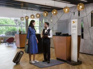 a man and a woman standing next to a counter at Mercure Budapest Castle Hill in Budapest