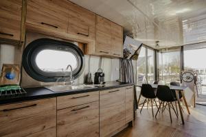 a kitchen with wooden cabinets and a table and chairs at Houseboat Uitgeest with Rooftop Terrace | 4 Guests in Uitgeest