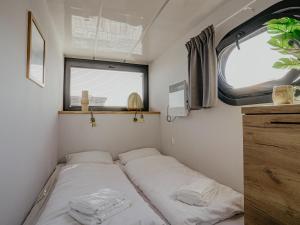 a bed in a small room with a window at Houseboat Uitgeest with Rooftop Terrace | 4 Guests in Uitgeest