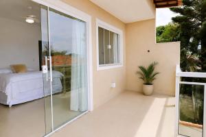 a bedroom with a balcony with a bed and a window at casa amplia y luminosa en porto da barra in Búzios