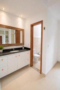 a bathroom with a toilet and a sink and a mirror at casa amplia y luminosa en porto da barra in Búzios