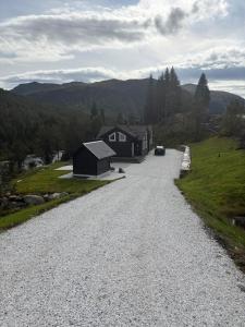 a gravel road with a house on the side of a hill at VillaElvesus in Vossevangen