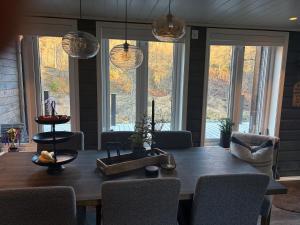 a dining room with a table and chairs and windows at VillaElvesus in Vossevangen