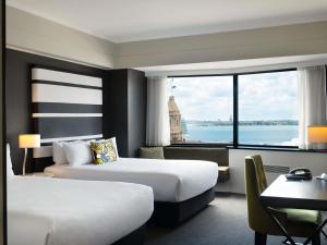 a hotel room with two beds and a large window at Mövenpick Hotel Auckland in Auckland +137 photos