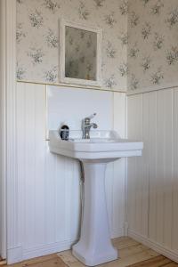 a white sink in a bathroom with flowers on the wall at Mjällbyhus Pensionat & Stugby in Sölvesborg +82 photos