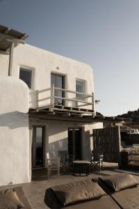 a white house with a balcony and a table and chairs at Villa Tonic by Mykonos Mood in Agios Ioannis Mykonos