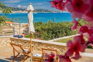 eine Terrasse mit zwei Stühlen und einem Sonnenschirm und das Meer in der Unterkunft Orientem Villa - Sea View Near Zante Town in Argassi