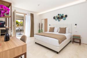a white bedroom with a bed and a desk and a table at Illumi's Hotel in Villasimius +144 photos