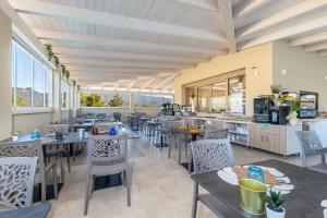 a restaurant with tables and chairs and windows at Illumi's Hotel in Villasimius