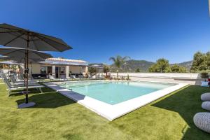 a swimming pool with an umbrella in a yard at Illumi's Hotel in Villasimius