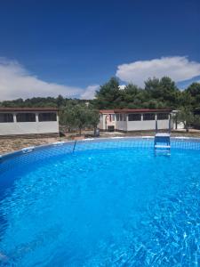 a large swimming pool with a blue chair in it at Mobile Home MEDITERRA in Pirovac