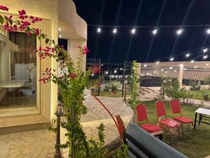 a patio with chairs and a table with pink flowers at شاليه إطلالة in Buraydah +18 photos