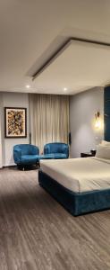 a bedroom with a bed and two blue chairs at Brick House Hotel Lahore in Lahore