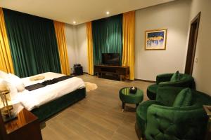 a hotel room with a bed and two chairs and a television at Brick House Hotel Lahore in Lahore