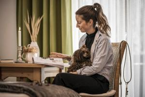 a woman sitting in a chair with a dog in her lap at Gästehaus Restaurant Wiesenheim in Uderns