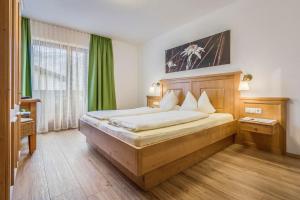 a bedroom with a large bed with green curtains at Gästehaus Restaurant Wiesenheim in Uderns +246 photos