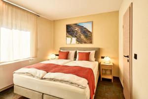 a bedroom with a large bed with orange pillows at Wohnen am Weingut - Über den Fässern in Briedel