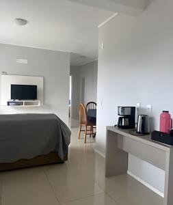 a bedroom with a bed and a desk with a microwave at Apartamento - 2 Quartos * Completo * Central in Bento Gonçalves