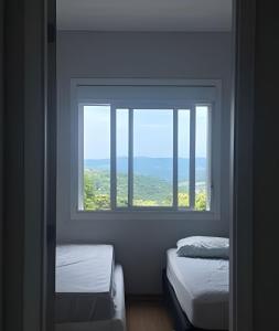 a room with two twin beds and a window at Apartamento - 2 Quartos * Completo * Central in Bento Gonçalves