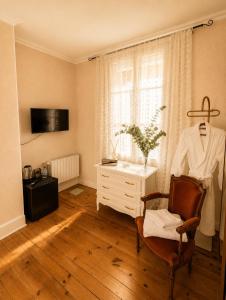 a room with a chair and a dresser and a window at La Cour Du Puits, Chambre Darjeeling in Cormeilles