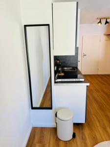 a white kitchen with a mirror and a stool at Apartment Altstadt Stralsund in Stralsund +3 photos