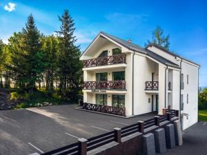 a white building with balconies and a fence at Hellene Snow Starý Smokovec in Starý Smokovec