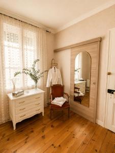 a room with a mirror and a chair and a dresser at La Cour Du Puits, Chambre Darjeeling in Cormeilles