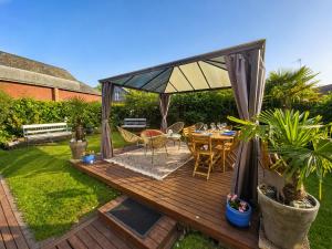 a wooden deck with a table and chairs in a garden at La Cour Du Puits, Chambre Darjeeling in Cormeilles