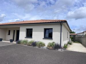 a white house with plants in a parking lot at Studio La Petite Forge in Castelnau-de-Médoc