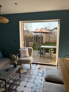 a living room with a chair and a table and a patio at Meadow Cottage Cambridge in Trumpington +13 photos