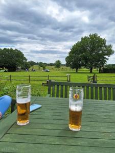 two glasses of beer sitting on a wooden table at Care Ashore Guest Rooms in Cranleigh