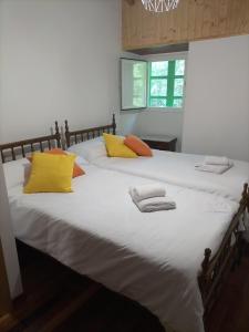 a large white bed with yellow and orange pillows at Muiño Verde in Loña del Monte