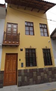 a yellow house with a balcony and a door at CASA ETEN Hospedaje Boutique - centro histórico de Cajamarca in Cajamarca
