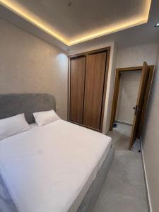 a bedroom with a white bed and a door at اقامة هبة 2 in Yebha