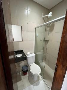 a bathroom with a toilet and a glass shower at Hotel Piracema in Caruaru