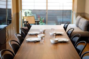 a wooden table with chairs and plates and glasses on it at Shiosai HIRADO in Hirado
