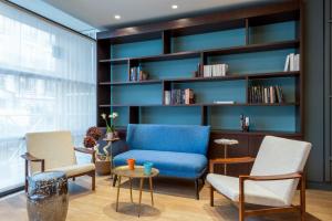 a living room with a blue couch and chairs at Hôtel Sanso by HappyCulture in Paris