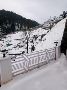 a snow covered hill with a fence and a town at Celestia peaks in Bhowāli