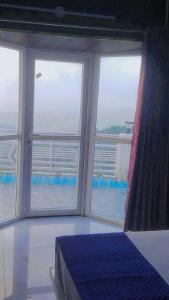 a bedroom with three windows and a bed with a view of the ocean at Celestia peaks in Bhowāli +7 photos