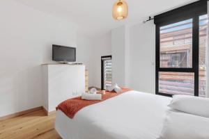 a white bedroom with a bed and a tv at Modern townhouse with parking in Toulouse +6 photos