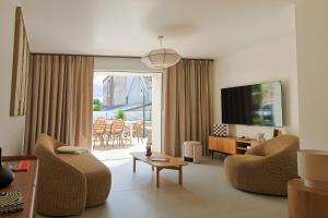 a living room with two chairs and a tv at Maison VENELL Concarneau - Spa, Balnéo, Sauna & Jardin - Calme en Centre-ville in Concarneau
