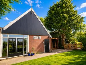 a barn with a black roof at Holiday Home de Binnengouw incl Hottub in Hoogwoud