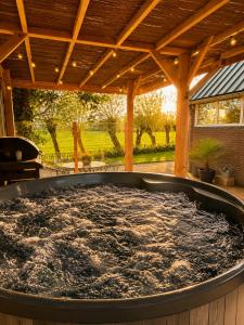 a large hot tub sitting under a covered patio at Holiday Home de Binnengouw incl Hottub in Hoogwoud
