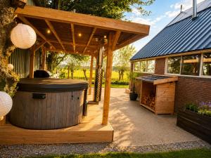 a wooden gazebo with a hot tub on a patio at Holiday Home de Binnengouw incl Hottub in Hoogwoud